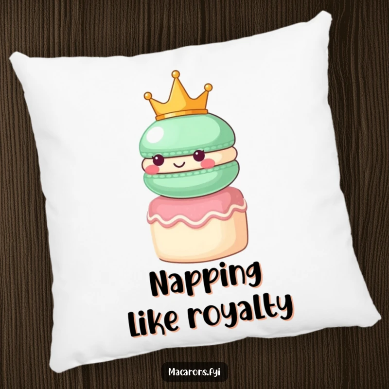 Funny macaron character wearing a small crown, looking regal atop a tiny cake, featured on a plush pillow.