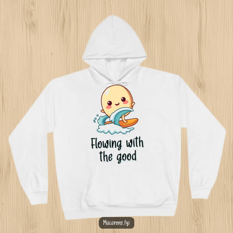 Funny macaron character happily surfing on a miniature wave, designed for cozy warmth in this comfortable hoodie.