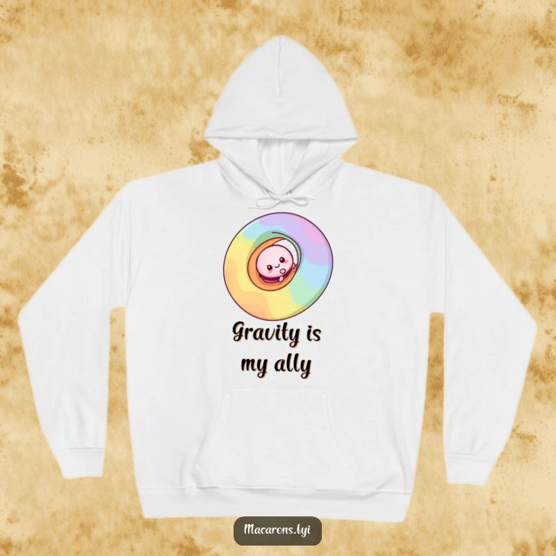 Cozy funny macaron character enjoying a playful slide down a colorful rainbow swirl, printed on a warm hoodie.