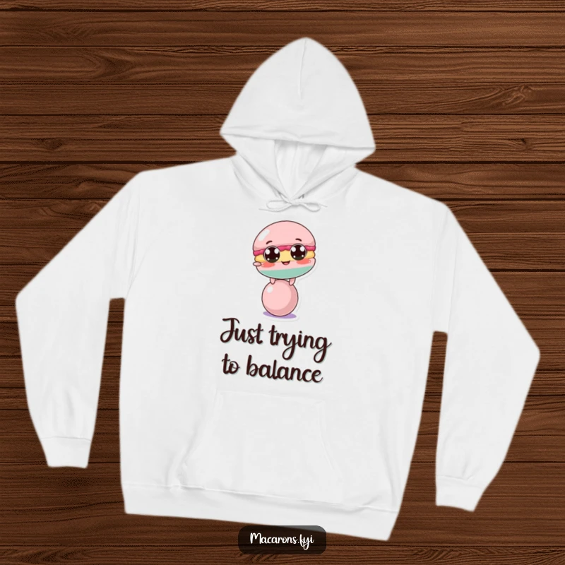 Funny macaron character precariously balanced on a ball, printed on a soft and warm hoodie for ultimate comfort.